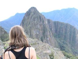 Frau von Hinten, steht vor einer weiten Bergkette in Peru