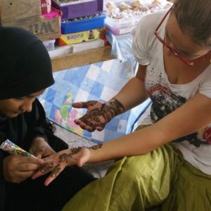Ein Mädchen bekommt Henna-Tattoos auf ihre Hände gemalt
