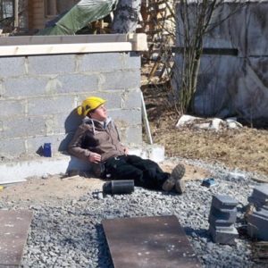 Ein Junge lehnt in der Sonne an einer Steinmauer auf einer Baustelle